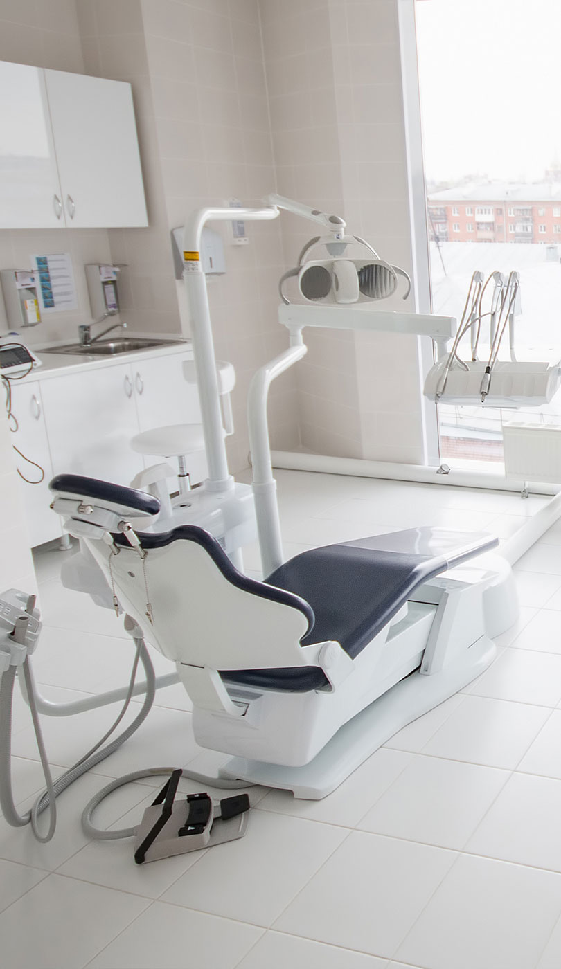 The image shows a modern dental or medical office interior with a dental chair, equipment, and a clean, professional environment.